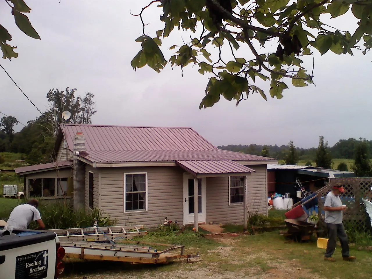 Crew finishing a mauve metal roof on a small farmhouse in Greenbelt
