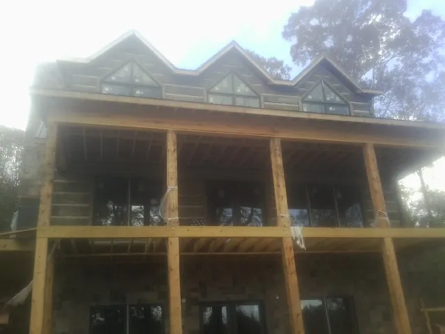 Dormers and porch framing on a large log home under construction — Roof Coating work by our crew in Greenbelt