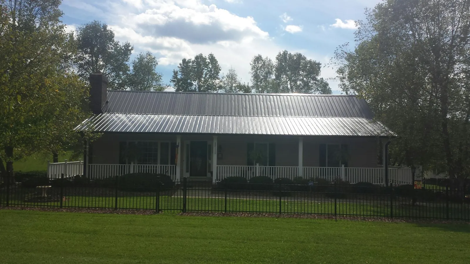 Gray metal roof on a brick ranch with a full width front porch — Gutter Guard Installation work by our crew in Greenbelt