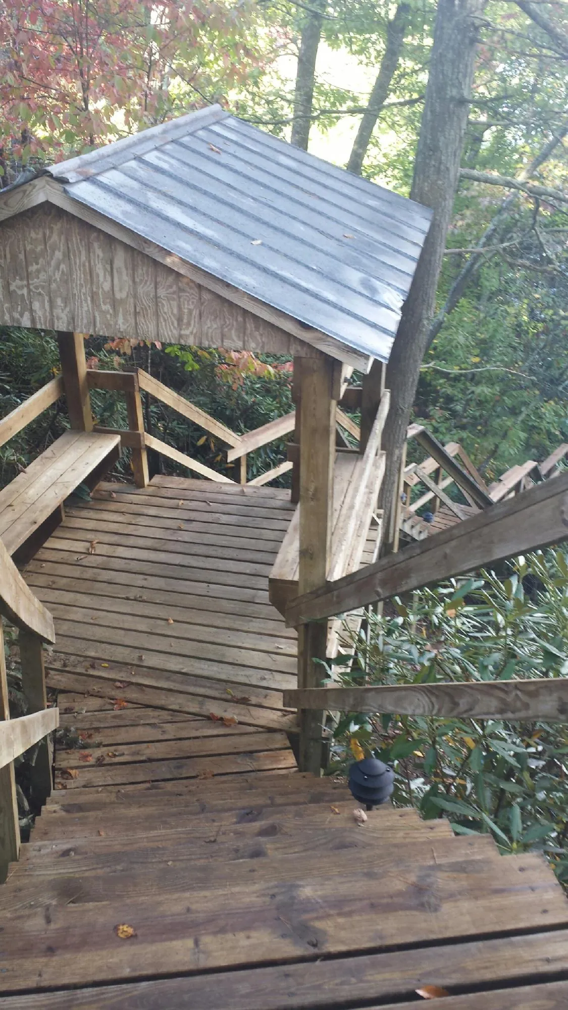 Metal roofed shelter over wooden steps on a wooded walkway — Skylight Repair & Installation work by our crew in Greenbelt