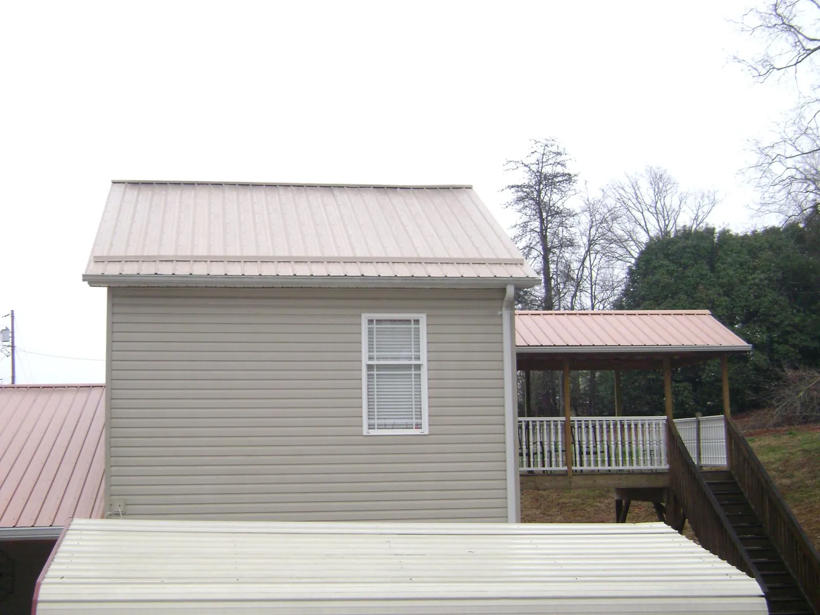 Tan metal roofs on a two story addition and attached porch, from a Roof Replacement job in Greenbelt