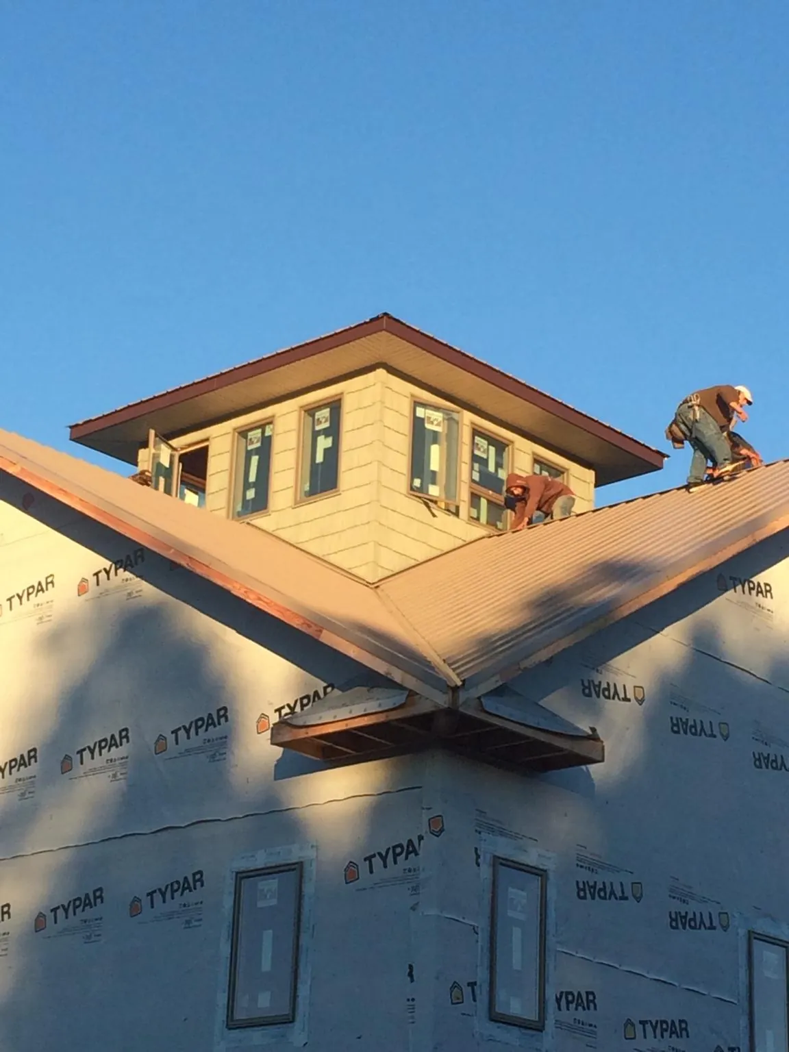 Roofers working around a rooftop cupola on a new metal roof at sunset — Roof Waterproofing in Greenbelt by Roofing Brothers